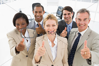 Diverse close business team smiling up at camera giving thumbs up