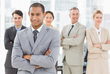 Young businessman smiling at camera with team behind him