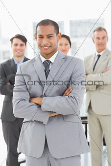 Businessman smiling at camera with team behind him