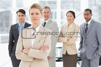 Businesswoman looking at camera with team behind her