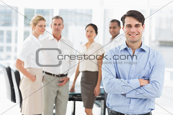 Happy businessman standing with team behind him
