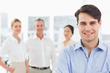 Smiling businessman standing with team behind him