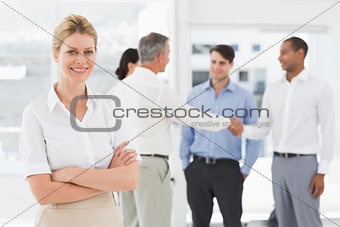 Blonde businesswoman with team behind her smiling at camera