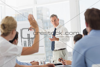 Senior businessman presenting bar chart to his colleagues asking questions