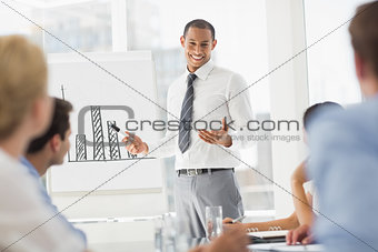 Happy young businessman presenting bar chart to co workers