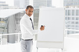 Young businessman presenting at whiteboard with marker