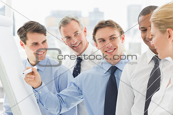 Young businessman writing on whiteboard with colleagues