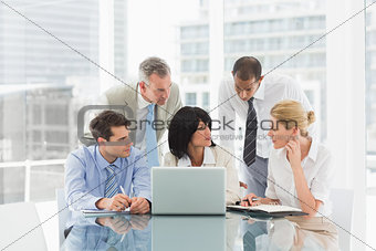 Business people gathered around laptop discussing