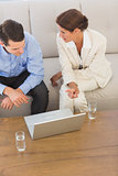 Business partners working on laptop together sitting on sofa