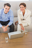 Business partners smiling at camera sitting on sofa