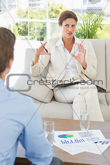 Businesswoman talking with colleague sitting on sofa
