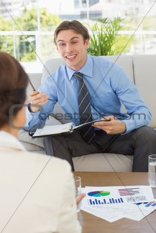 Happy businessman scheduling with colleague sitting on sofa