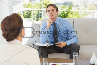 Young businessman listening to colleague sitting on couch