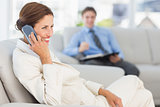 Smiling businesswoman on the phone sitting on couch