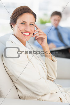Cheerful businesswoman on the phone sitting on couch