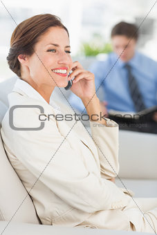 Cheerful businesswoman on the phone sitting on sofa