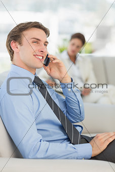 Happy businessman on the phone sitting on sofa