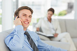 Smiling young businessman on the phone sitting on couch