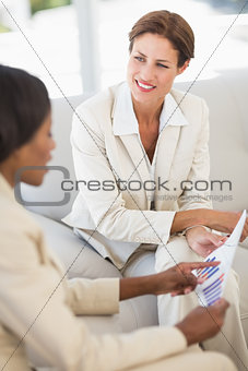 Happy businesswomen meeting to go over charts on the couch