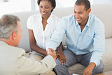 Young couple shaking hands with salesman on the sofa