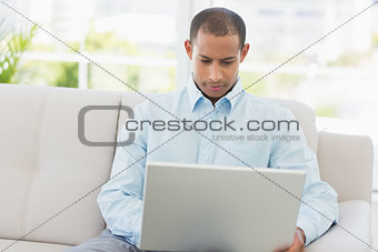 Young businessman working on laptop on the couch