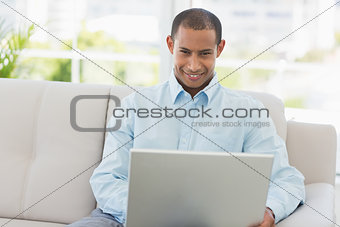 Smiling businessman working on laptop on the couch