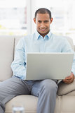 Happy businessman working on laptop on the couch