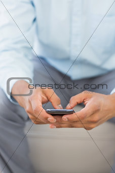 Man sending a text sitting on sofa