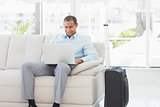 Happy businessman using laptop waiting to depart on business trip