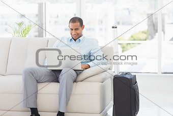 Happy businessman using laptop waiting to depart on business trip