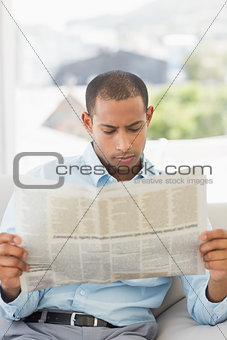 Serious businessman reading newspaper on the couch