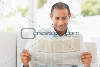 Smiling businessman reading newspaper on the couch