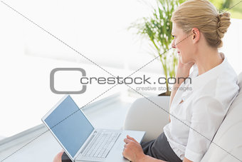 Businesswoman sitting on the couch working on laptop