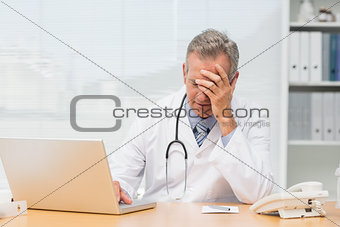 Stressed doctor sitting at his desk