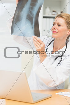 Doctor studying an xray sitting at her desk
