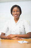 Happy nurse smiling at camera sitting at desk