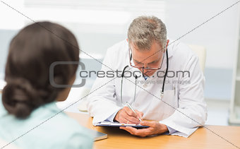 Doctor listening to his patient and taking notes