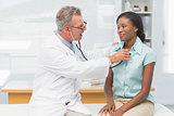 Doctor listening to cheerful patients chest with stethoscope