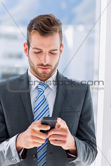 Handsome young businessman text messaging