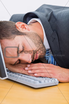 Businessman resting with head over keyboard at desk