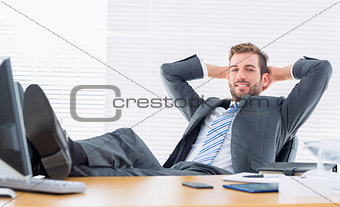 Relaxed confident businessman sitting with legs on desk