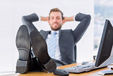 Relaxed businessman sitting with legs on desk at office