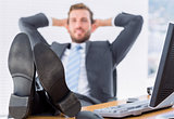 Relaxed businessman sitting with legs on desk
