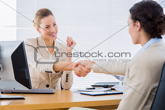 Smartly dressed women shaking hands in business meeting