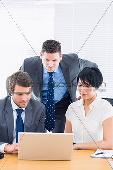 Colleagues using laptop at office desk