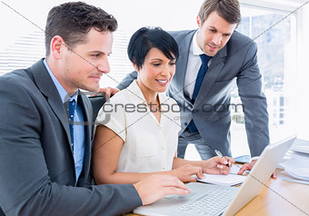 Young colleagues using laptop at office desk