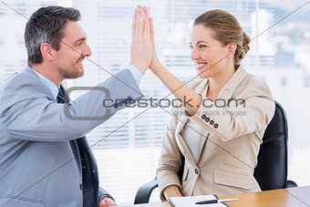 Colleagues giving high five in business meeting