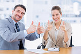 Businessman and woman gesturing thumbs up
