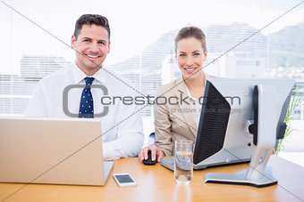 Smartly dressed colleagues using computer and laptop