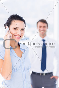Woman on call with male colleague in background